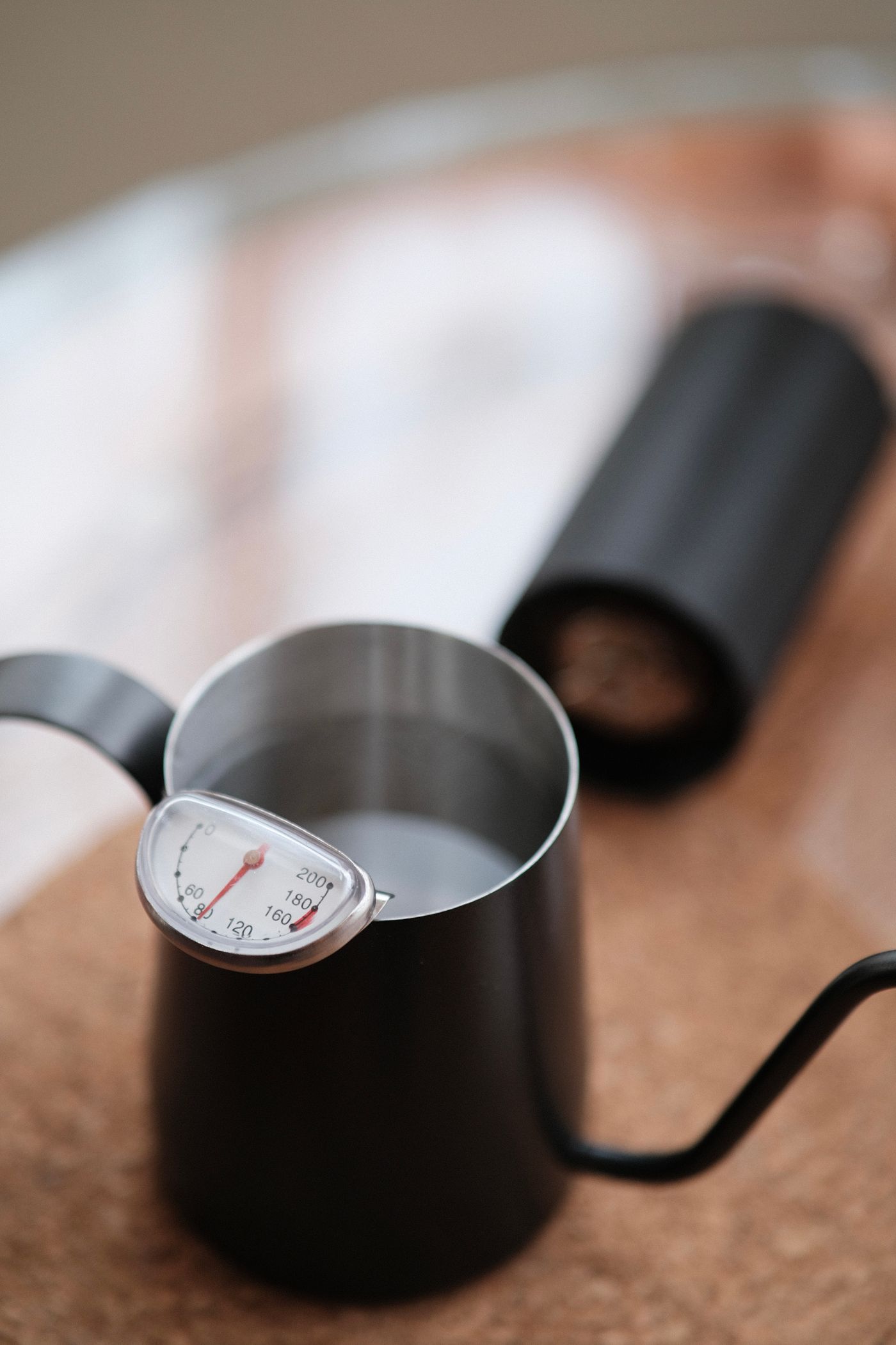 A thermometer probe in a pot of milk