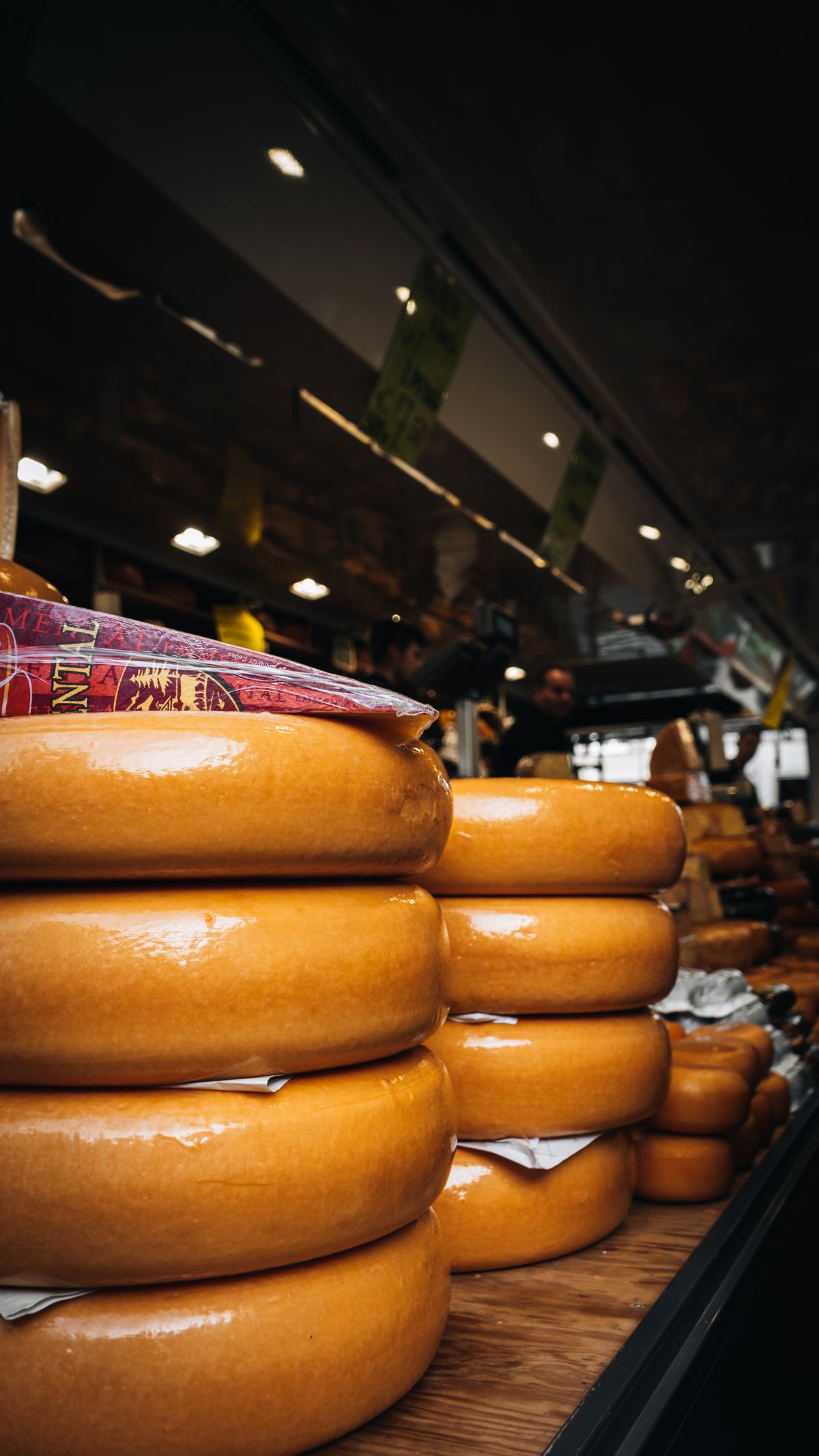 Stacked hard cheese wheels on a market table