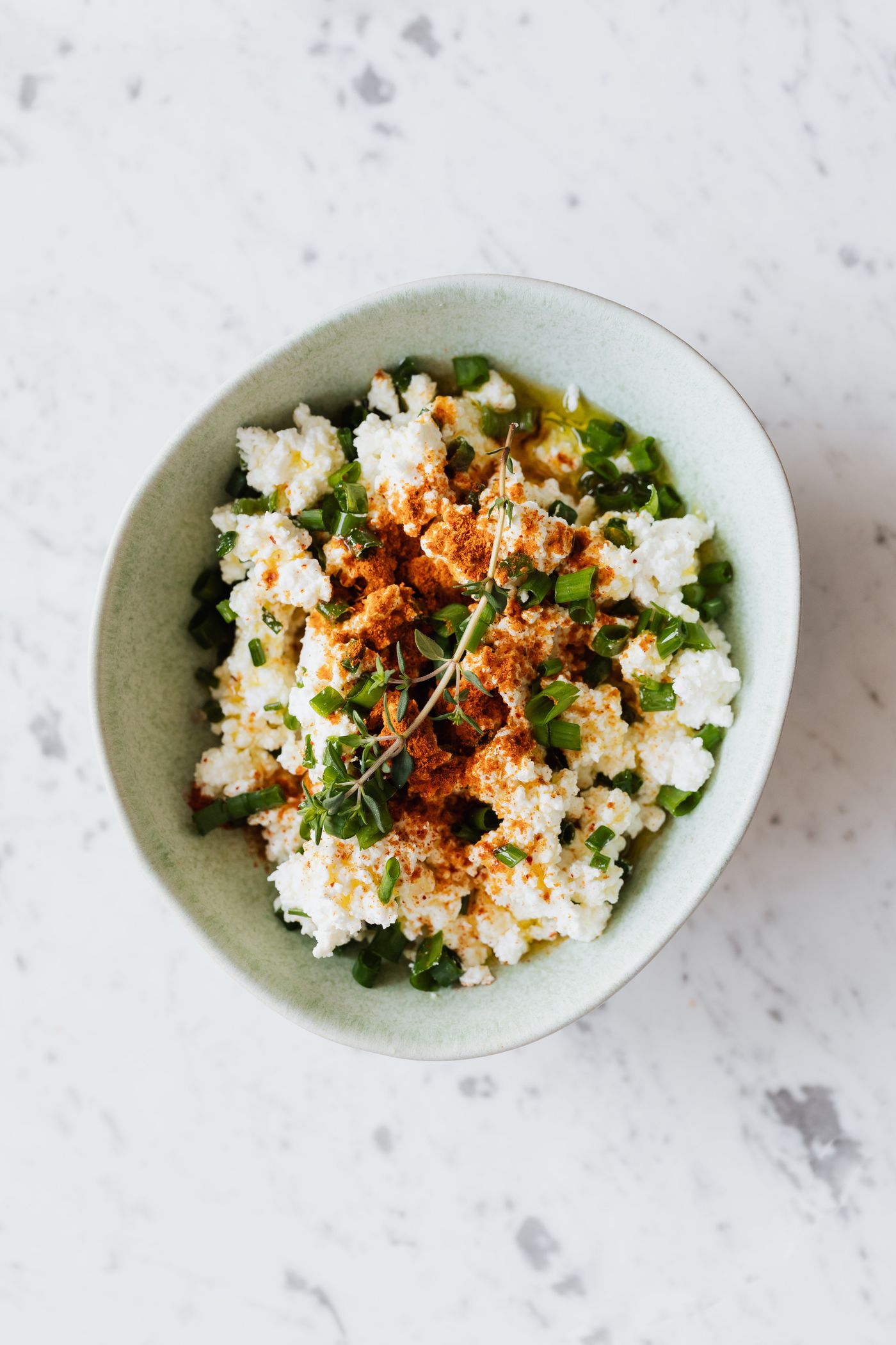 A bowl of fresh cottage cheese with herbs and oil