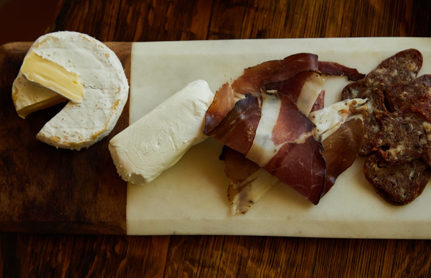 A goat cheese log on a board with cured meat