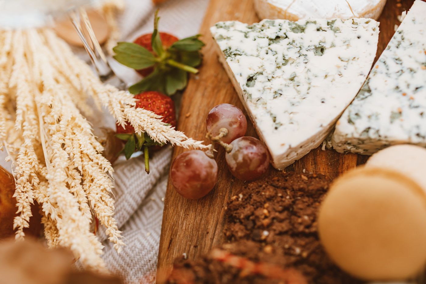 A cut of blue cheese with green veins on a wooden board