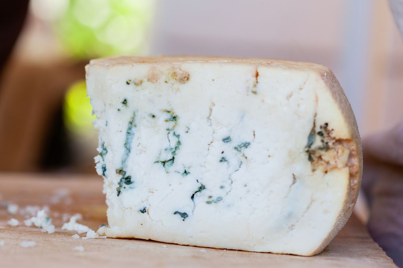 A wedge of blue-veined cheese on wood